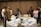A group of diverse individuals collaborating around a table with documents and laptops.