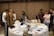 Team collaborating over technical documents and laptops in a bright meeting room.