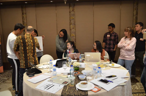 A collaborative team meeting around a table with documents and laptops, illustrating operational organization.