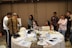 A diverse group of professionals collaborating around a table with laptops and documents.