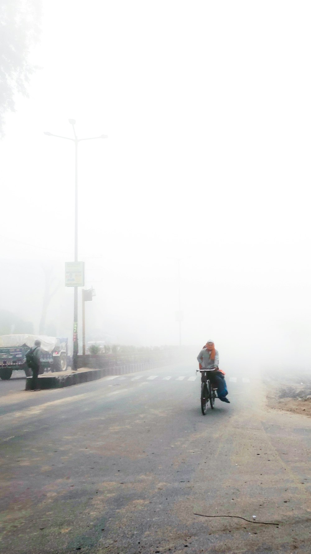 man in orange jacket riding bicycle on road during daytime