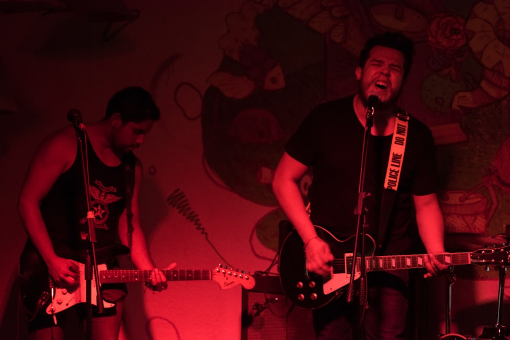 man in black crew neck t-shirt playing guitar