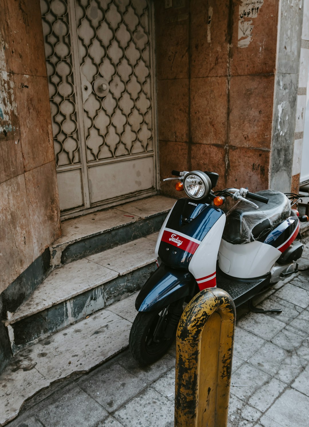 white and black motor scooter parked beside brown brick wall