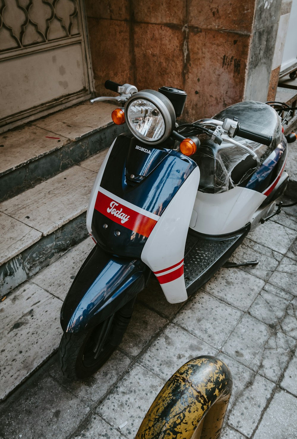 blue and white motor scooter parked beside brown brick wall