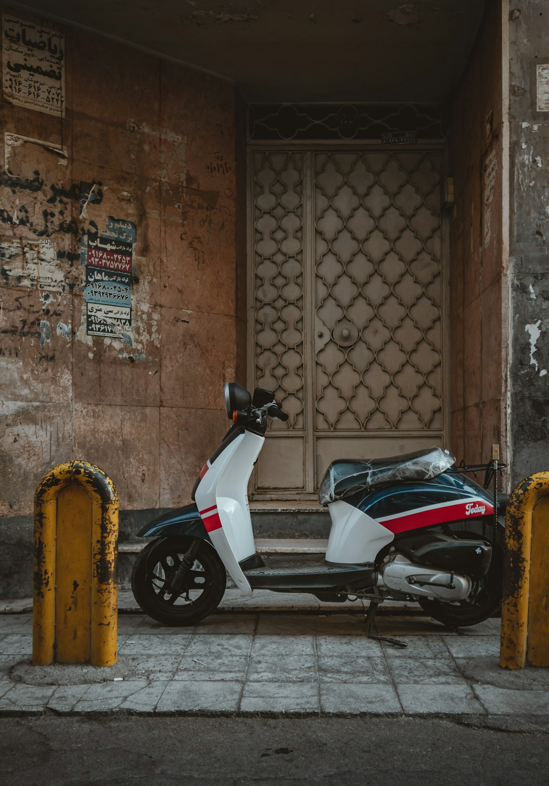 white and black motor scooter parked beside brown brick wall