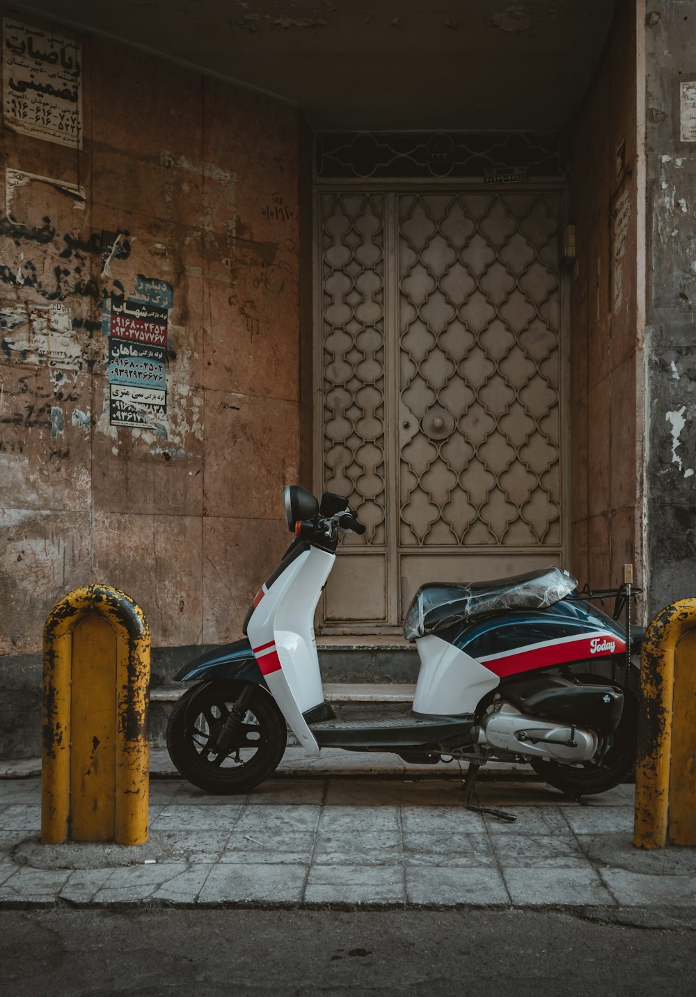 white and black motor scooter parked beside brown brick wall