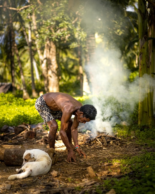 man in white and black checkered shirt sitting on ground with white short coated dog during in Siargao Island Philippines