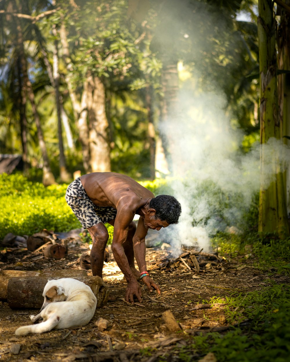 man in white and black checkered shirt sitting on ground with white short coated dog during