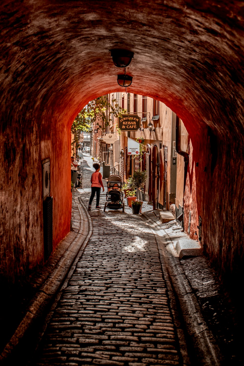 brown brick hallway with people walking on sidewalk during daytime