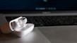 Wireless earbuds with charging case placed next to a laptop on a modern desk
