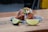 A vibrant taco resting on a wooden board, topped with a mix of colorful shredded vegetables, creamy sauce, and garnished with green herbs. A slice of lime sits nearby, enhancing the dish's appeal.