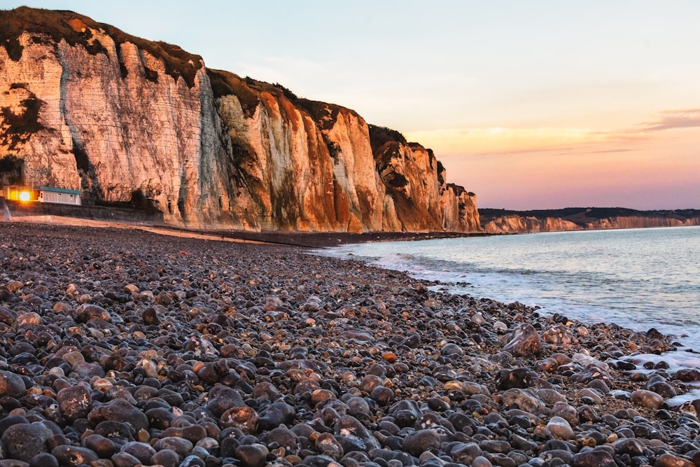 brown rocky mountain beside sea during daytime