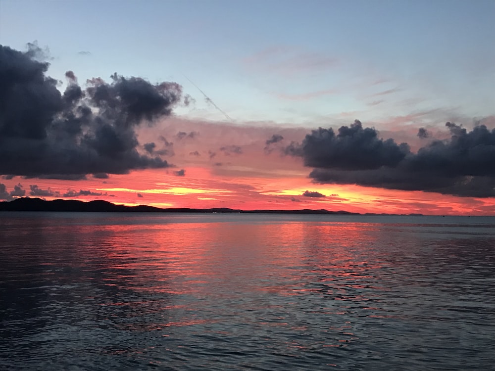 corpo de água sob o céu nublado durante o pôr do sol