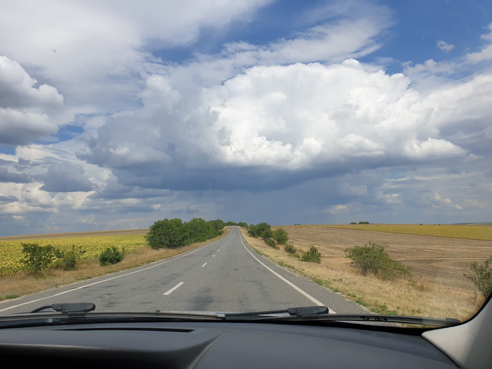 car on road under white clouds and blue sky during daytime