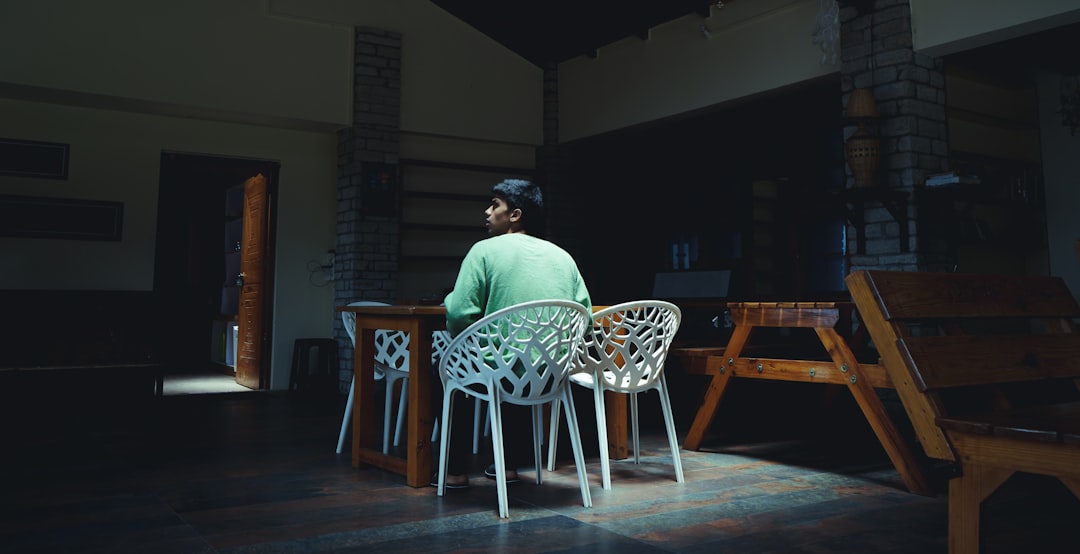 man in green shirt sitting on brown wooden chair