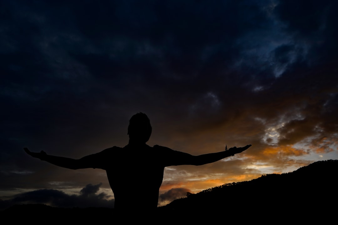 silhouette of man standing on hill during night time