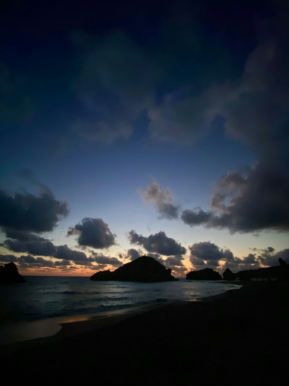 silhouette of mountain near body of water under cloudy sky during daytime