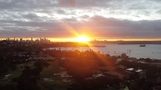 A vibrant sunrise over Thessaloniki's waterfront, with a plane soaring above the city skyline.