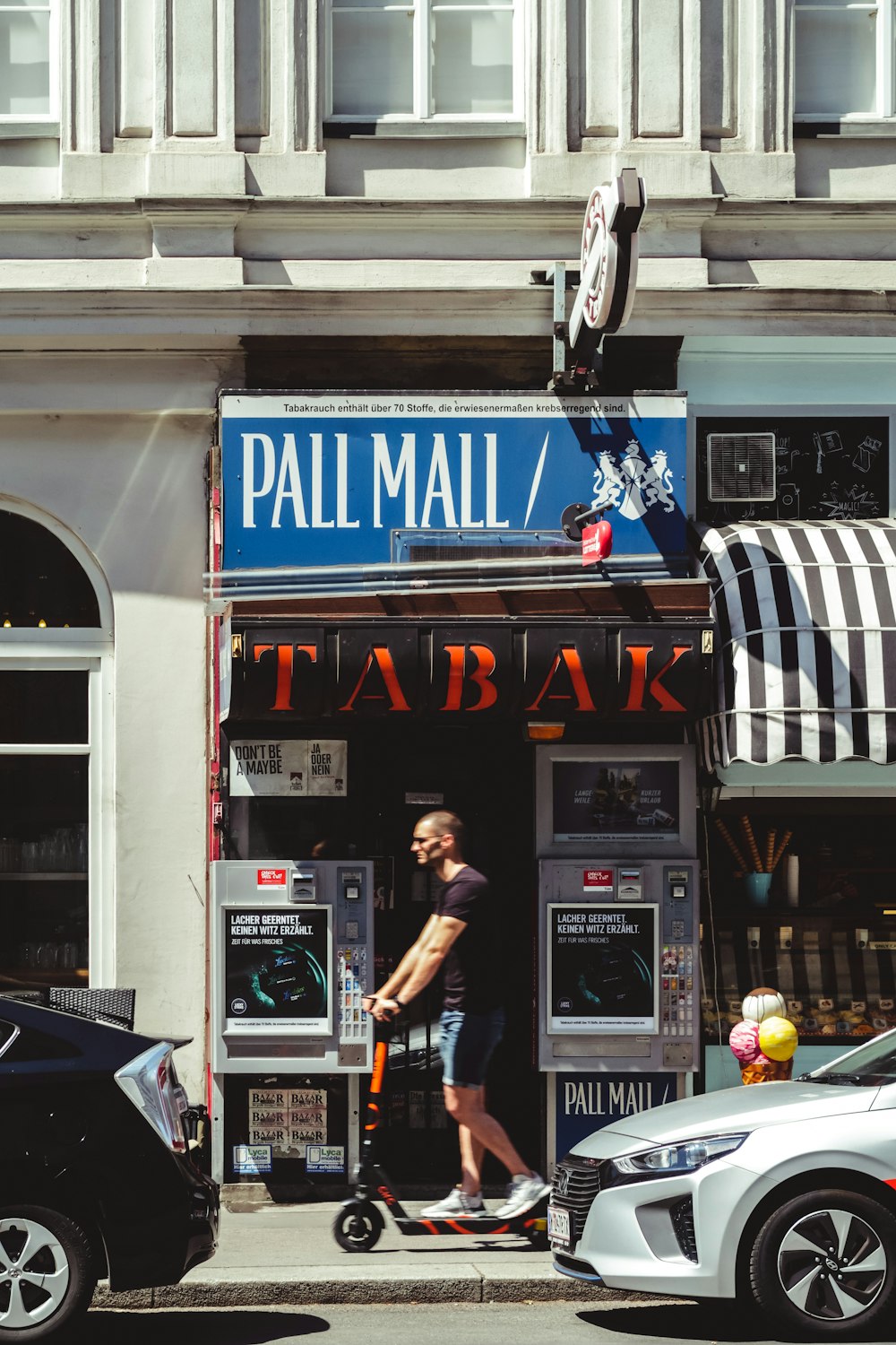 man in black t-shirt standing near black and white store during daytime