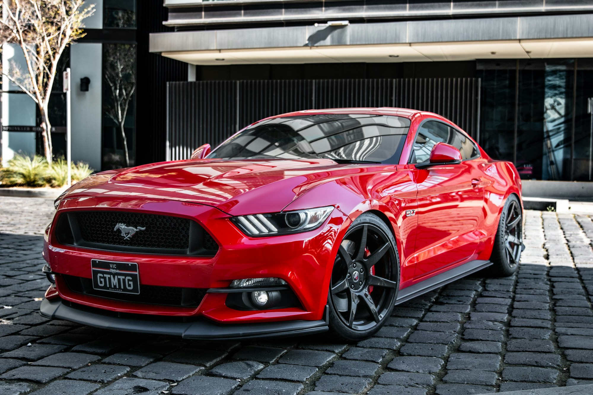 Red Ford Mustang 5.0 GT parked on a cobblestone driveway