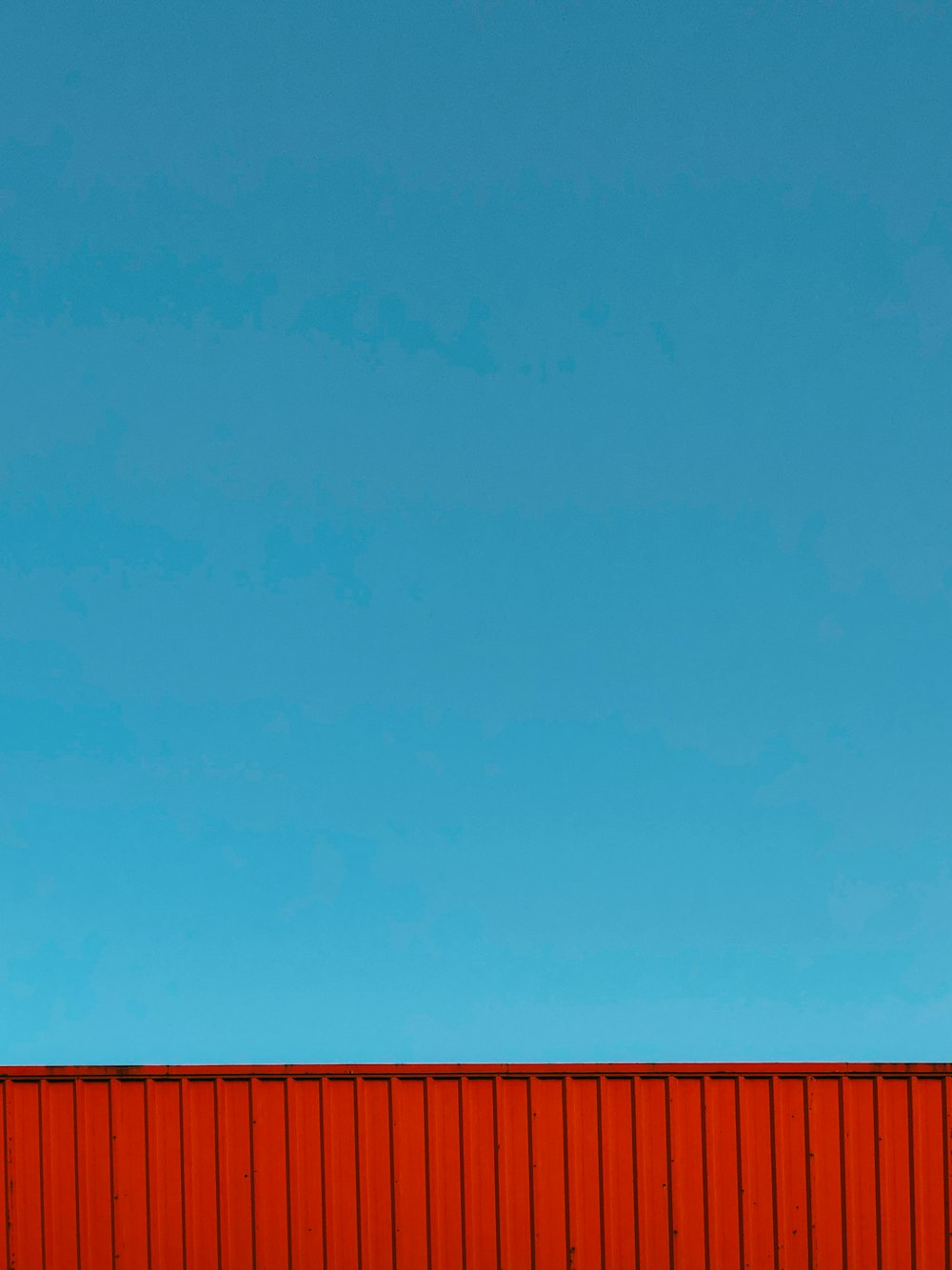 blue sky over red metal fence