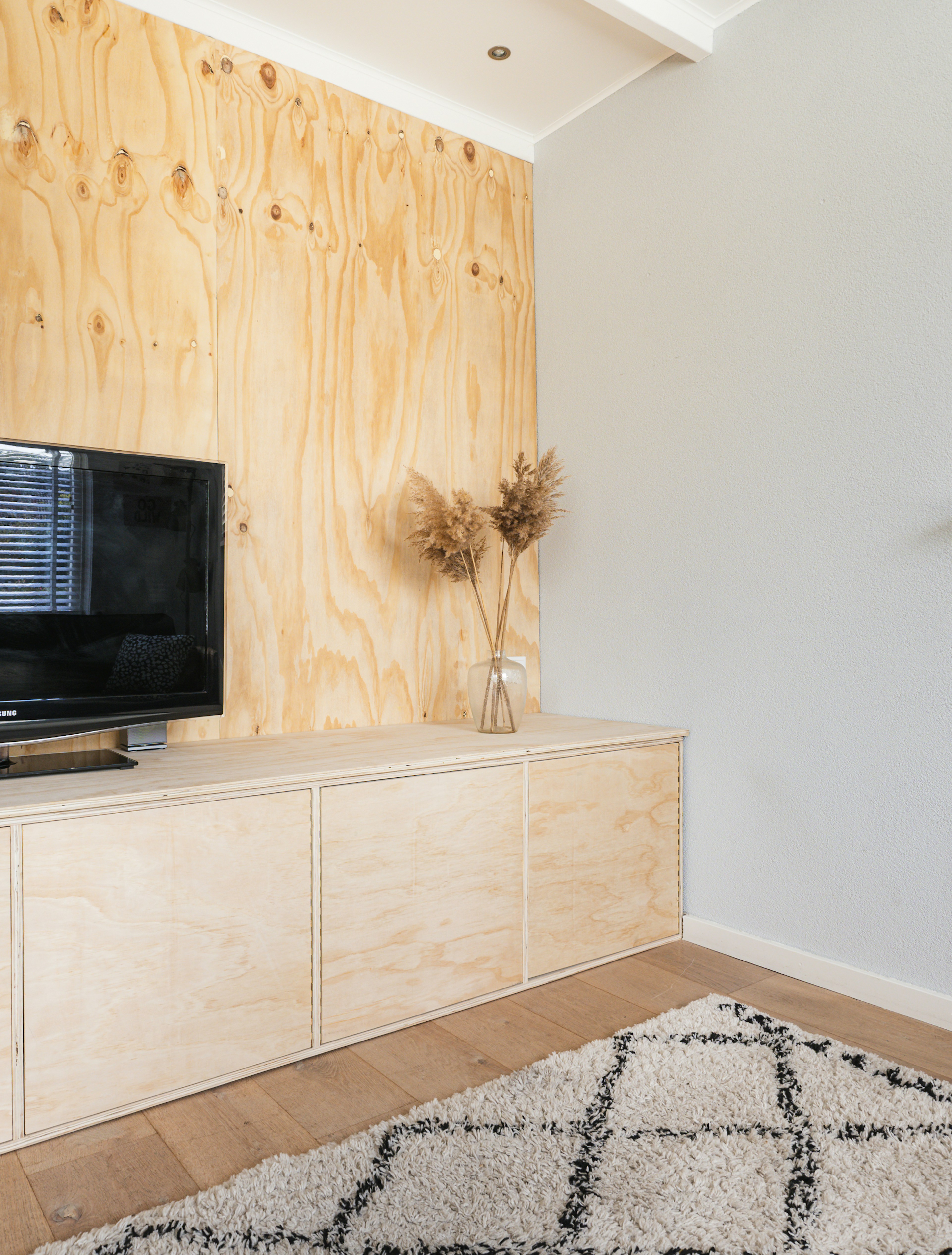 black flat screen tv on white wooden tv rack with plywood floors