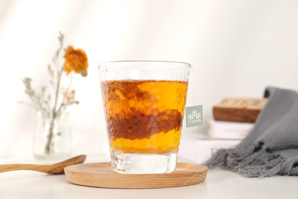 clear drinking glass with yellow liquid on brown wooden coaster