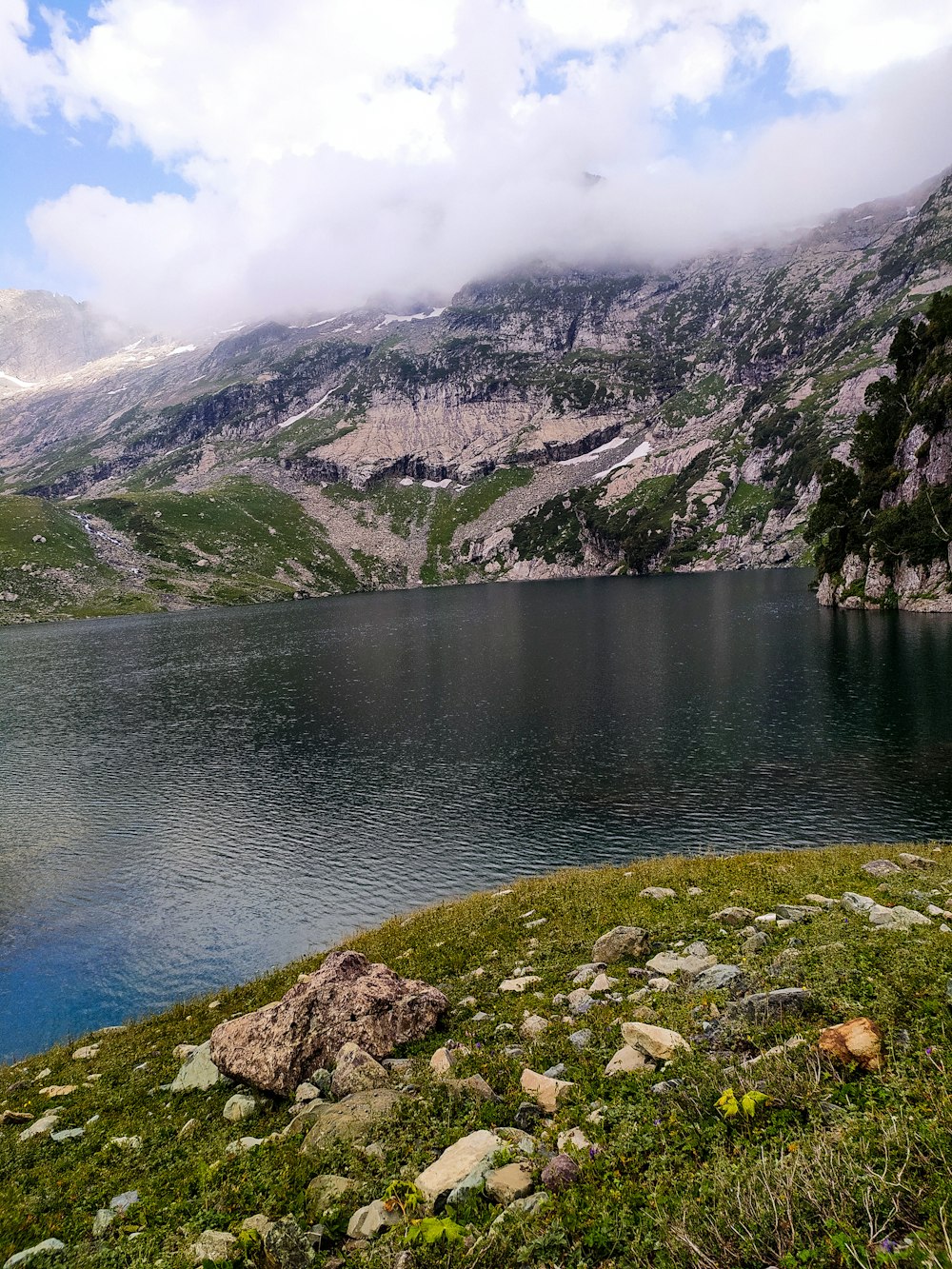 Montaña verde y marrón al lado del cuerpo de agua durante el día