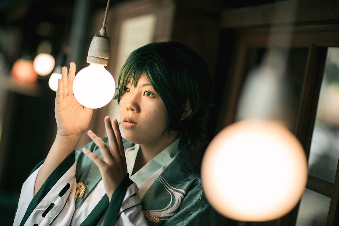 woman in green and white school uniform holding white light bulb