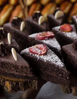 A rich chocolate cake topped with fresh strawberries and a dusting of powdered sugar.