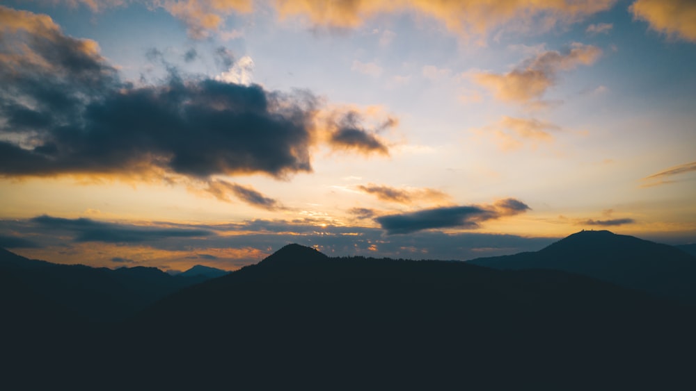 silhouette of mountain under cloudy sky during daytime