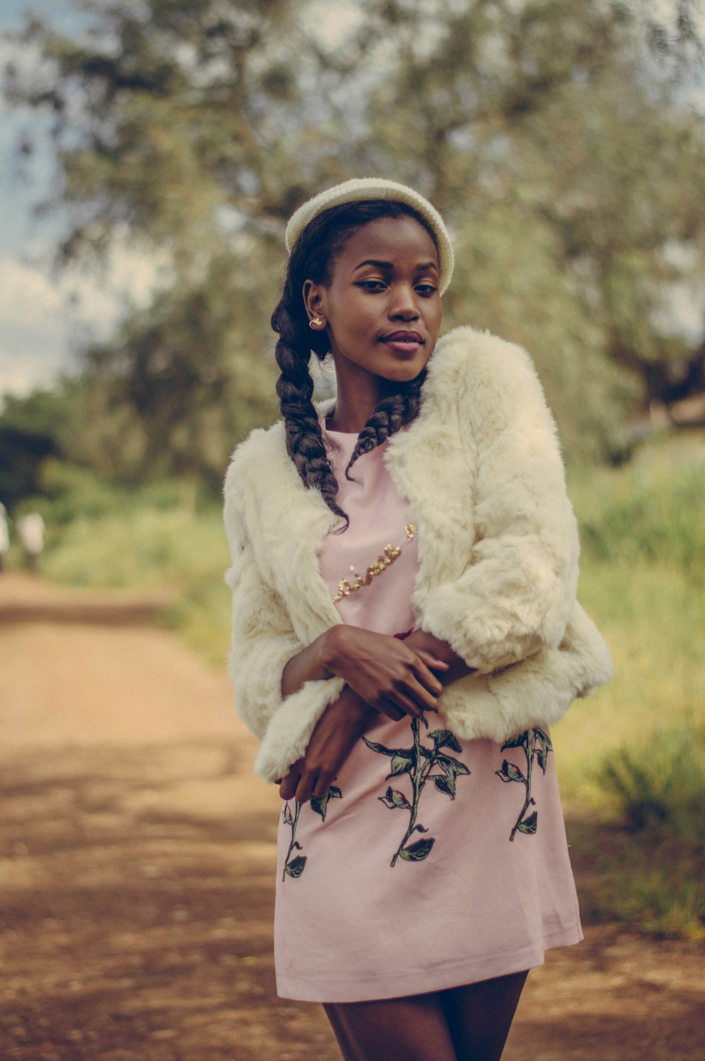 woman in white fur coat standing on brown dirt field during daytime