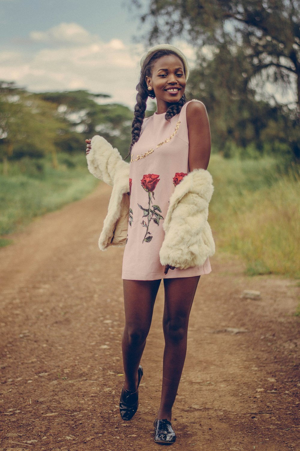 woman in white fur coat standing on dirt road during daytime