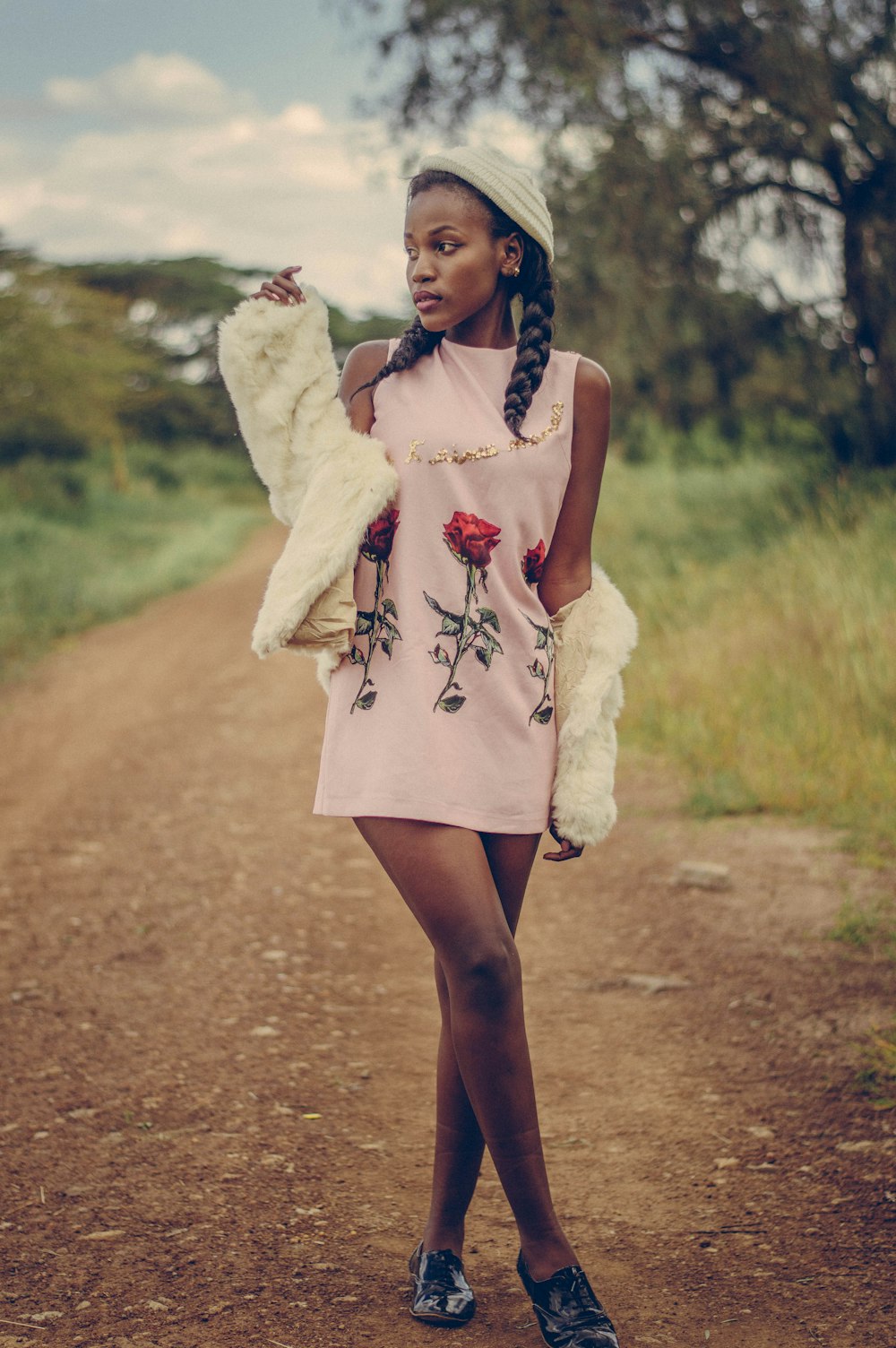 woman in white sleeveless dress standing on brown dirt road during daytime