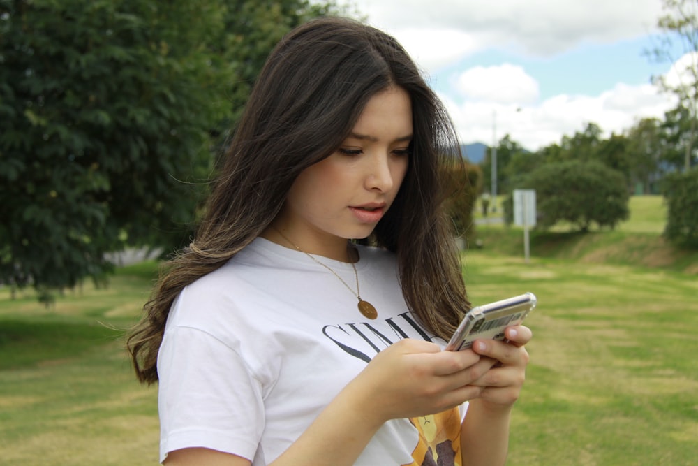 Mujer con camiseta blanca de cuello redondo con iPhone 6 plateado