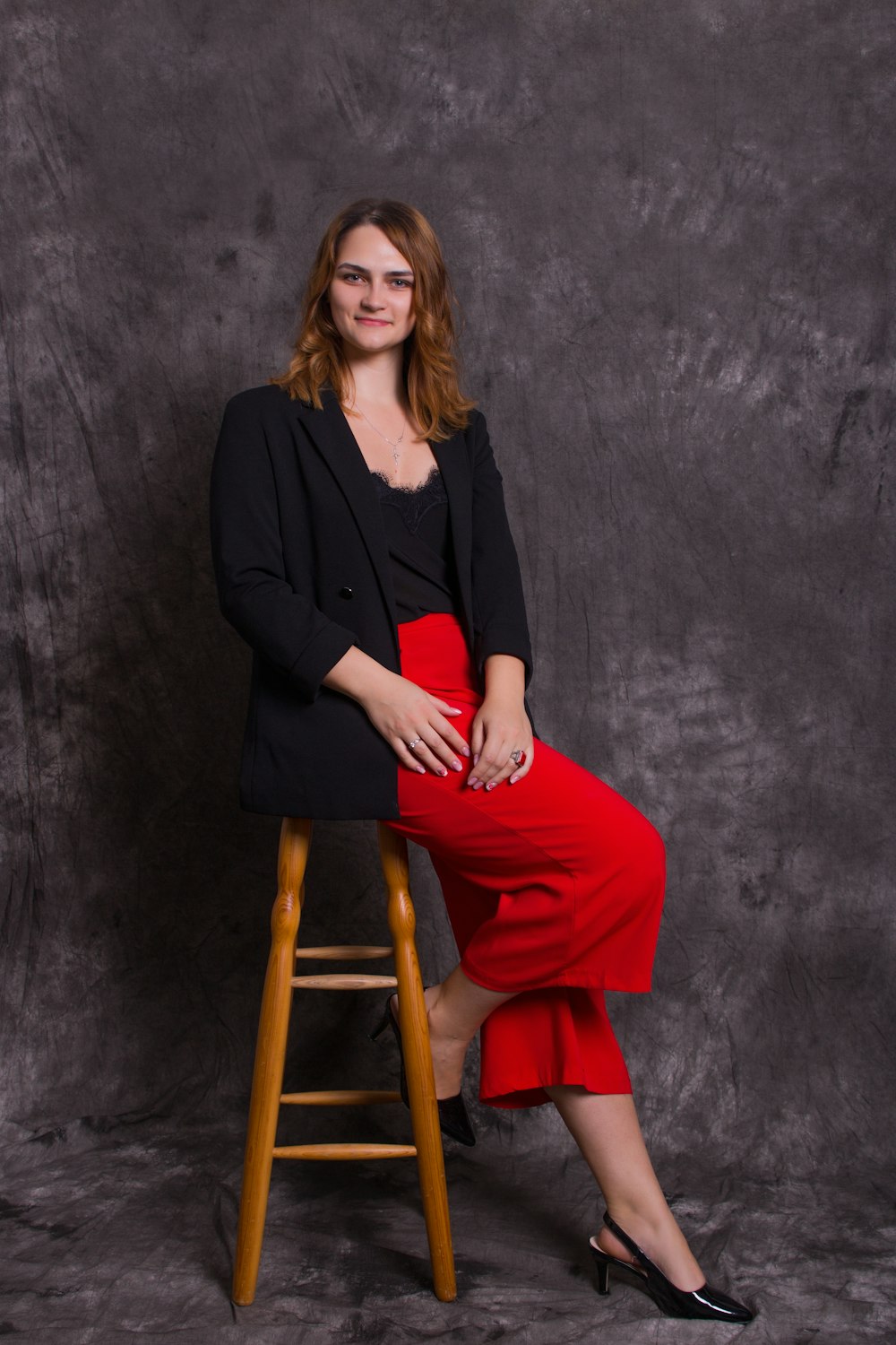 woman in black long sleeve shirt and red pants sitting on brown wooden seat