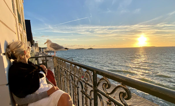 Cozy seaside apartment balcony overlooking turquoise waters of Costa Smeralda at sunset.