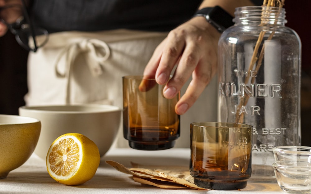 pessoa segurando copo transparente com suco de laranja