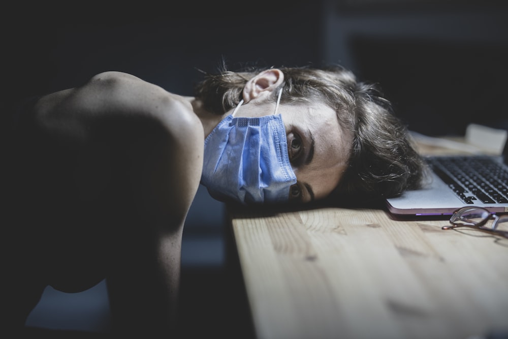 a person laying on a desk with a mask on