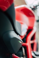 A close-up of a red motorcycle with sleek curves. The focus is on the side panel, which features a small decal with the colors of the Italian flag. Parts of the motorcycle frame and suspension are also visible.
