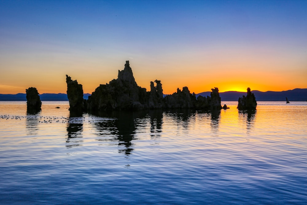 silhouette of mountain near body of water during sunset