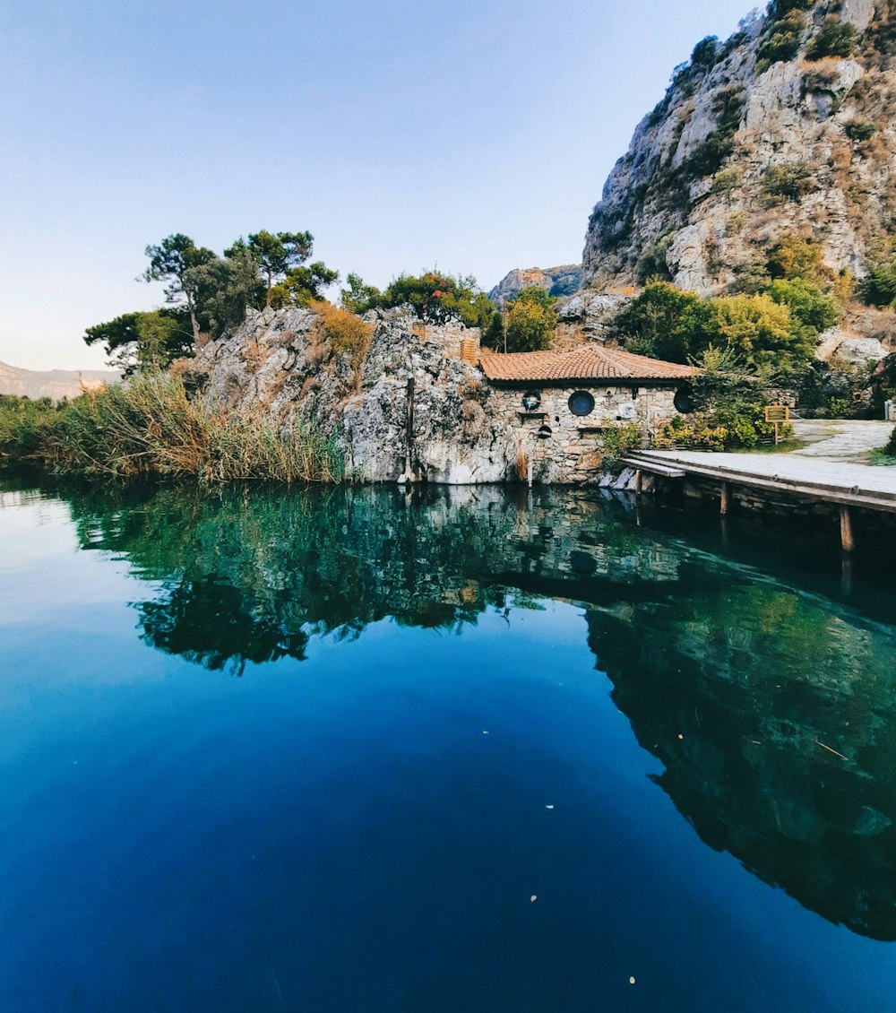 body of water near green trees and mountain during daytime