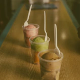 A colorful assortment of ice cream cups in pastel blue, cream, and pink hues on a wooden table
