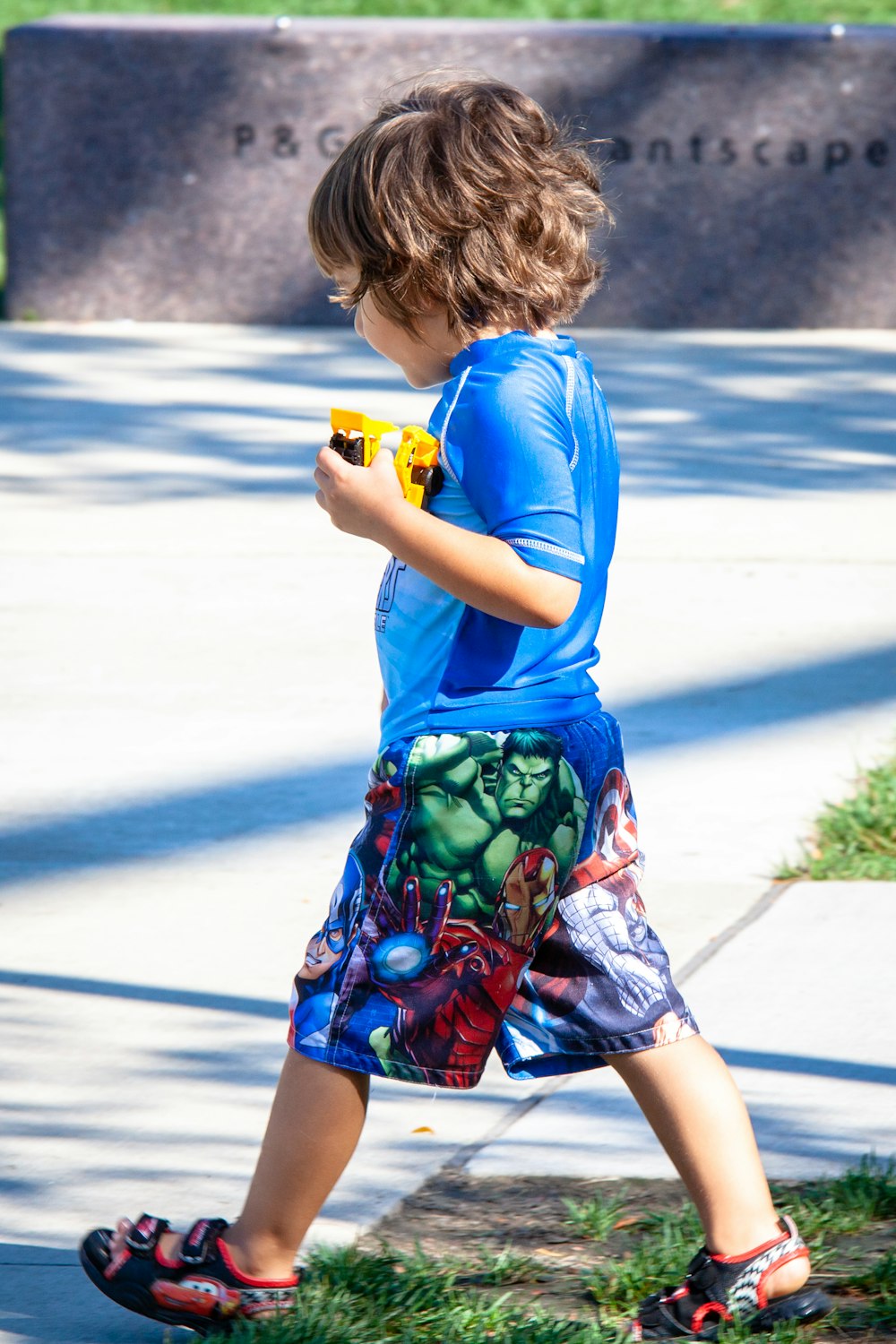 girl in blue t-shirt and green and red shorts holding yellow toy gun