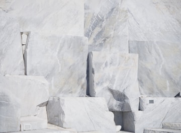 Rough marble blocks stacked in a sunlit warehouse.
