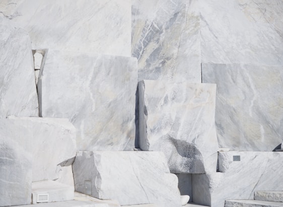Close-up of polished marble slabs stacked neatly in a sunlit warehouse, highlighting natural veins and textures.