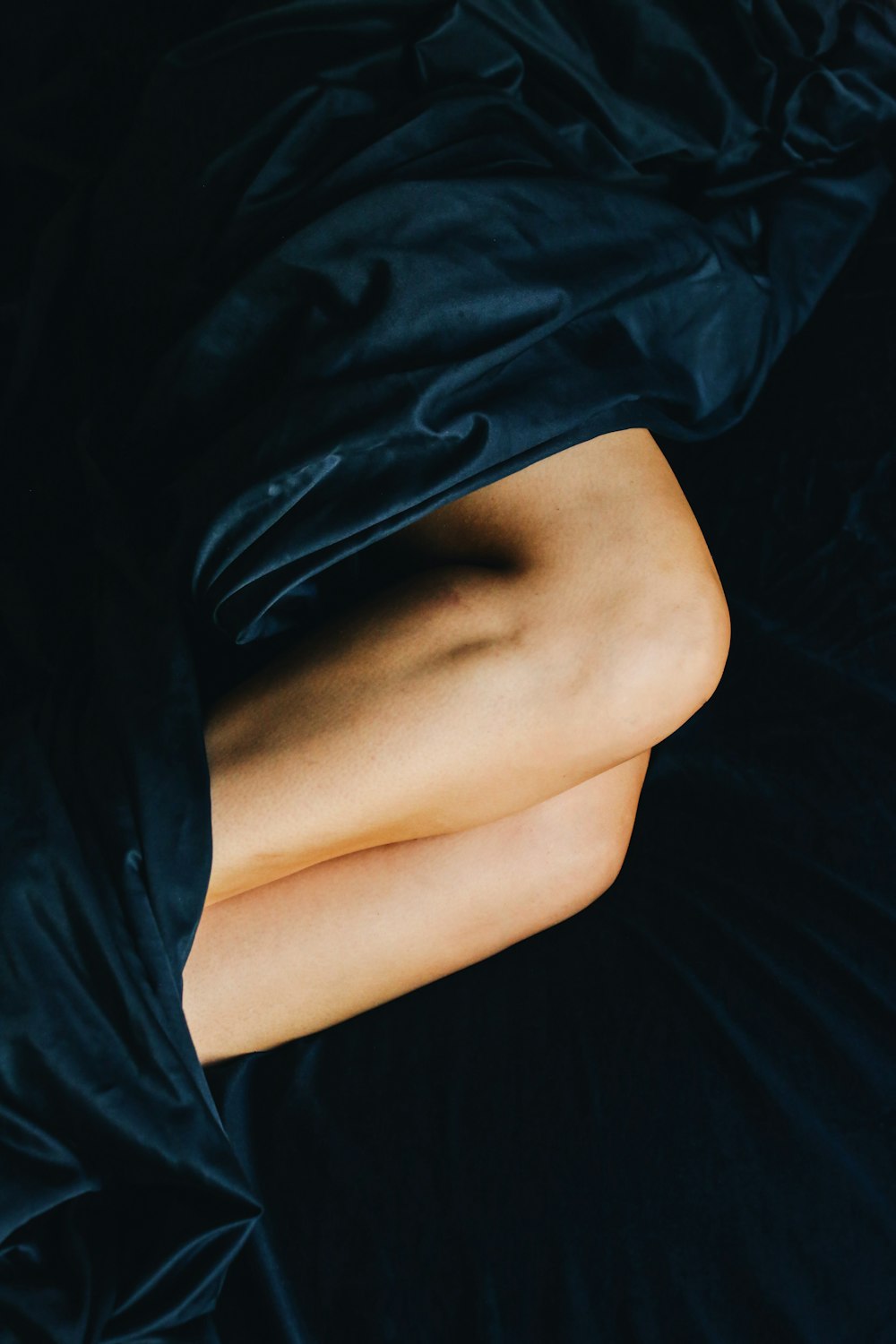 person in black shorts lying on black textile