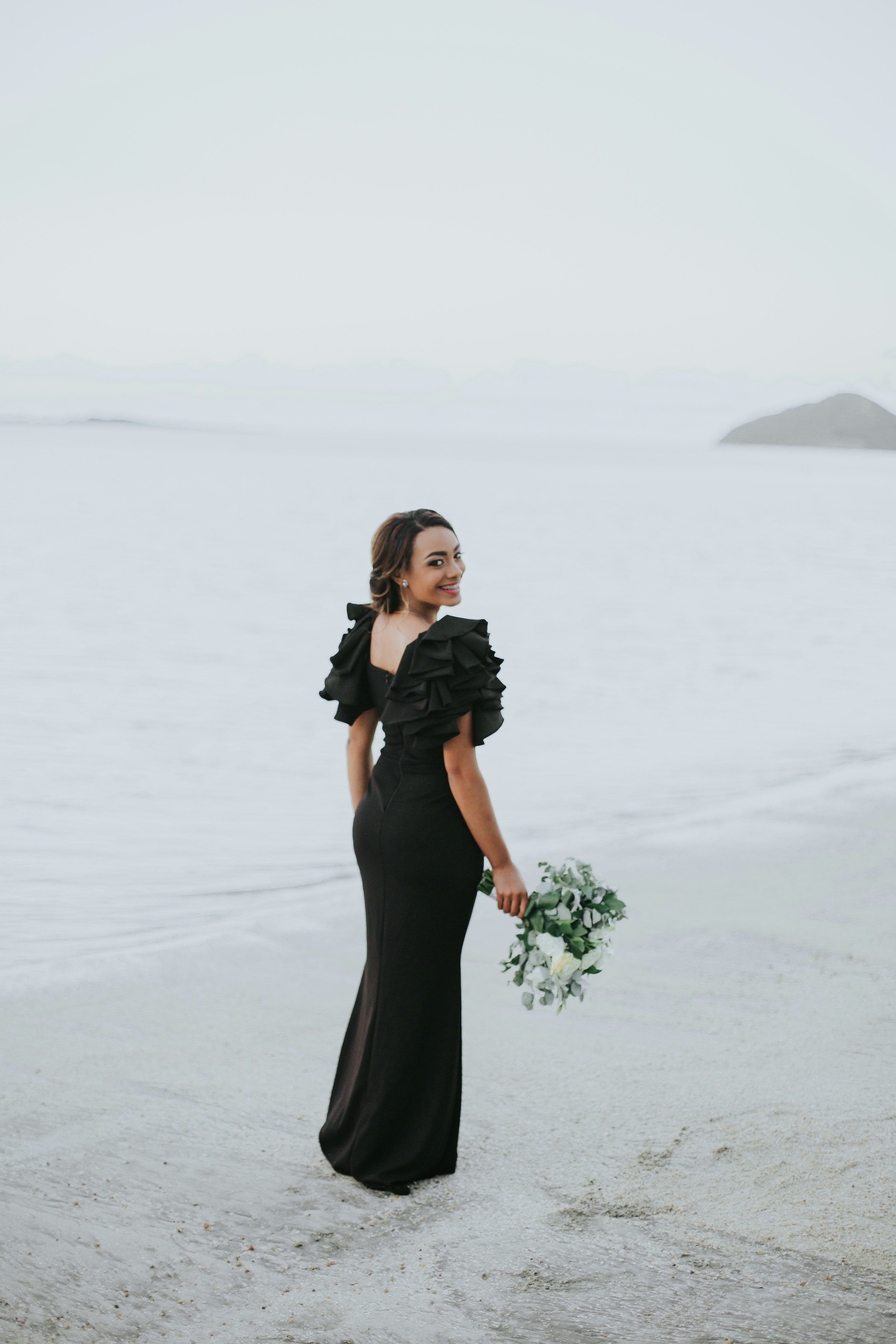 woman in black dress standing on white sand during daytime