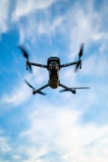 black and white drone flying under blue sky during daytime