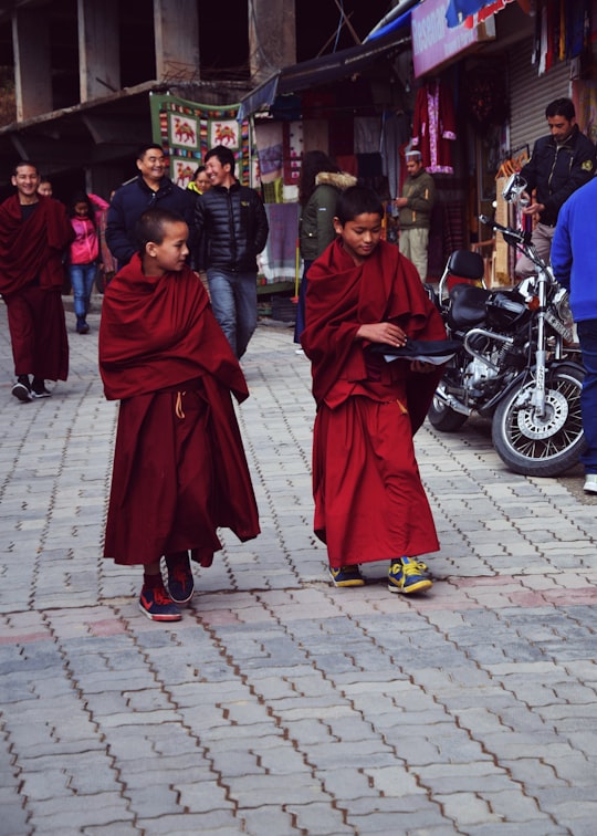 3 women in red hijab standing on sidewalk during daytime in McLeod Ganj India